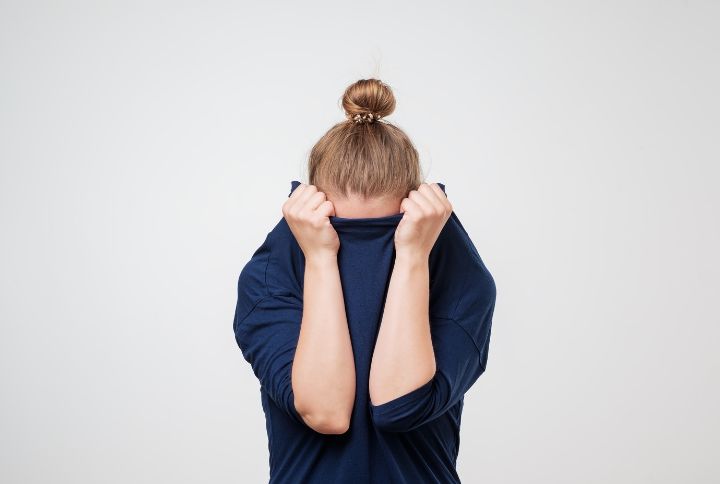 Phobie : image d'une femme souffrant de phobie. Elle se cache le visage avec son pull