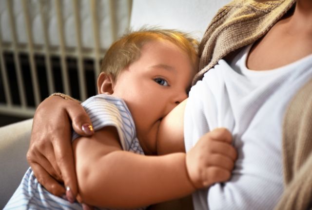 Allaitement maternel : semaine mondiale du 14 au 20 octobre 2024. Image d'un bébé qui tête le sein et regarde en même temps l'objectif.