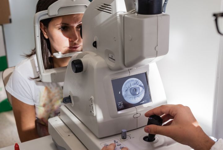 Décollement de la rétine : examen de la rétine chez le médecin. Une patiente regarde à travers un appareil.