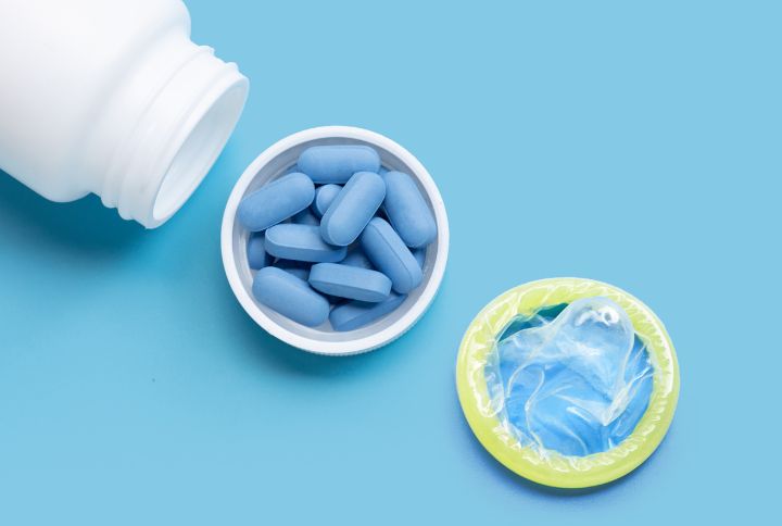 Tout savoir sur la PrEP prophylaxie prévention contre le VIH. Image d'un bocal en plastique de médicament, d'un bouchon plein de gélules bleues de Prep et d'un préservatif.