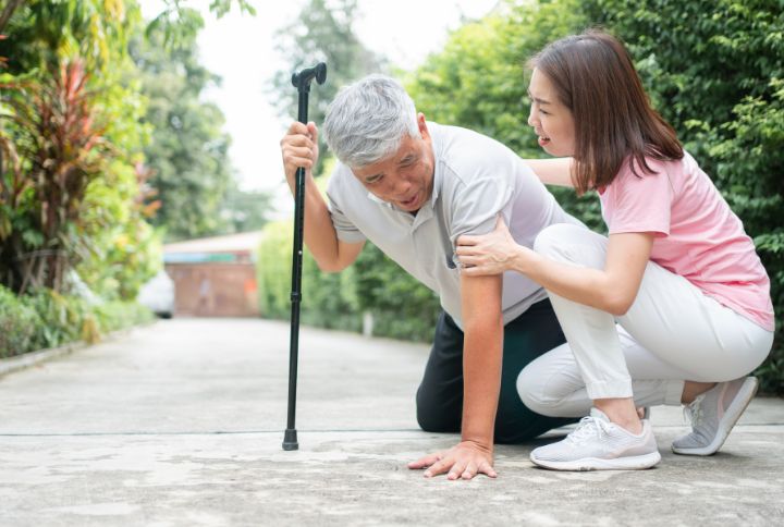 Myasthénie : un homme âgé, aux muscles fragilisés, est tombé à terre et est aidé par une femme.